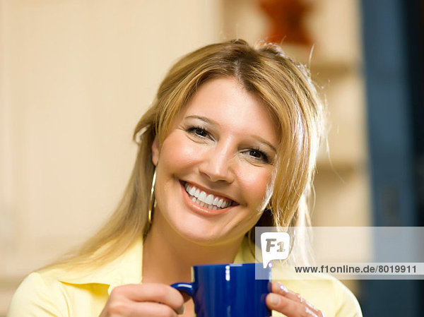 Mittlere erwachsene Frau hält Tasse und lächelt  Portrait