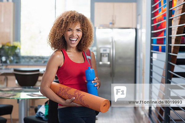 Mid adult woman in holding yoga mat and water bottle  portrait