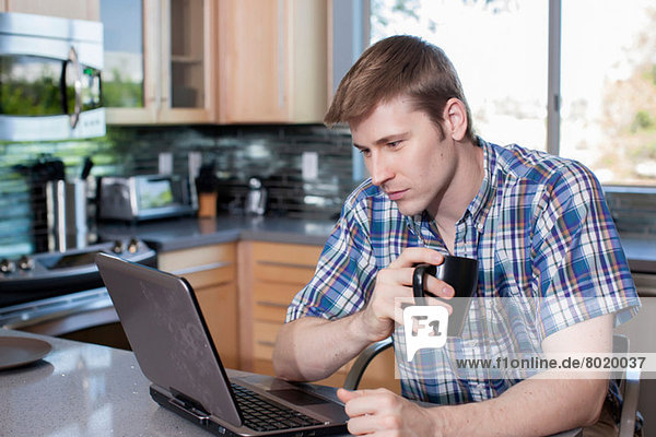 Mittlerer Erwachsener Mann mit Laptop in der Küche