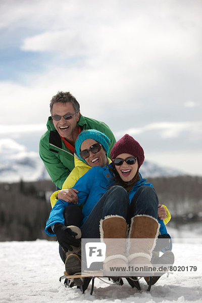 Three friends sitting on sledge in snow