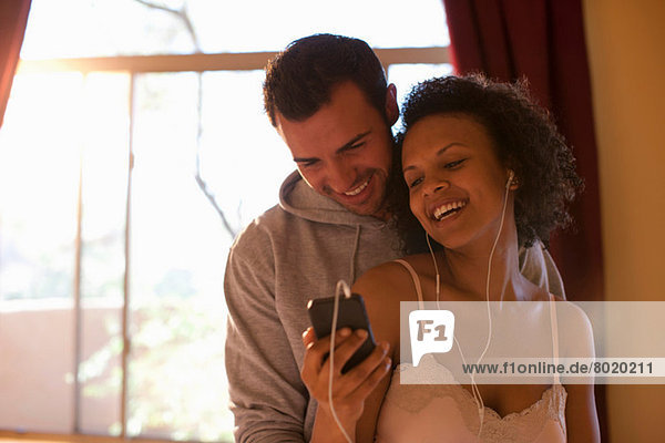 Young couple listening to mp3 player in hotel room  smiling