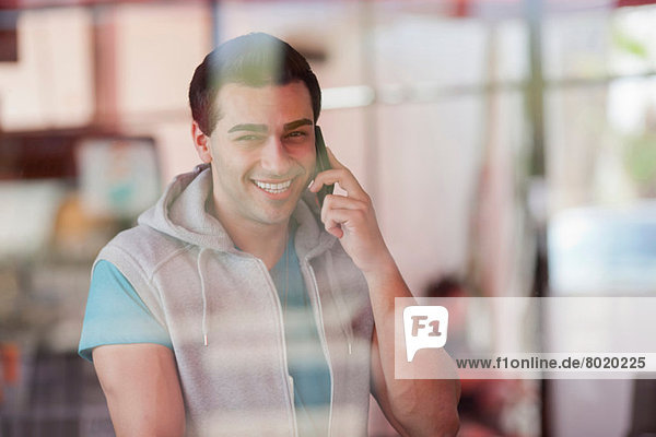 Young man using mobile phone in window of diner  smiling