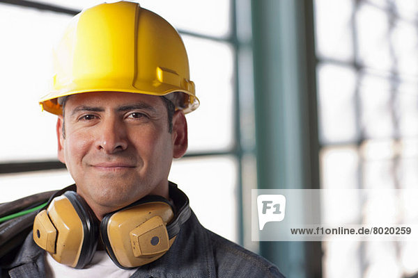 Reife Bauarbeiter mit Schutzhelm und Gehörschutz  lächelnd