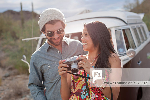 Junge Frau hält Kamera mit Freund auf Roadtrip  lächelnd