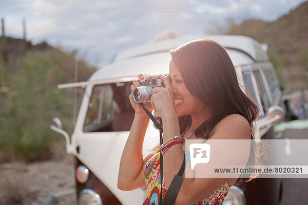 Young woman taking photograph on road trip  smiling
