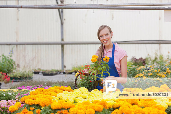 Mittlere erwachsene Frau mit Blumen im Gartencenter  lächelnd