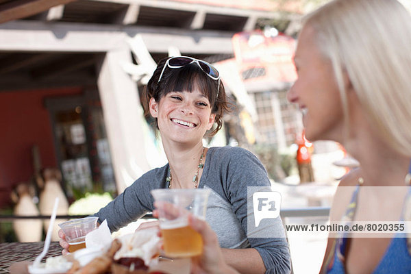 Freundinnen bei einem Drink im Outdoor-Café  lächelnd