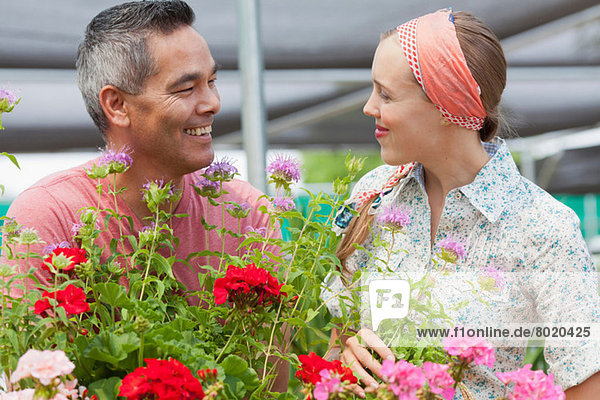 Mature man and mid adult woman shopping in garden centre  smiling