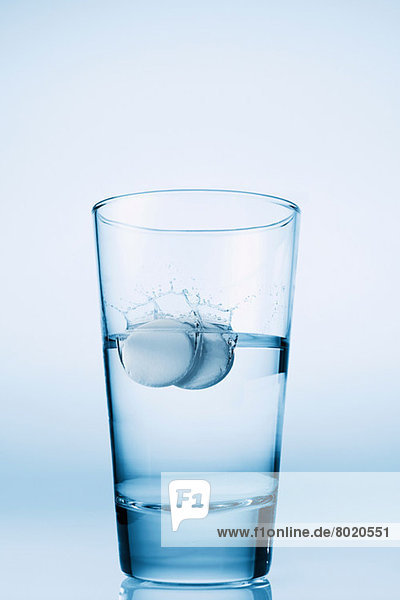 In ein Glas Wasser fallende Tabletten