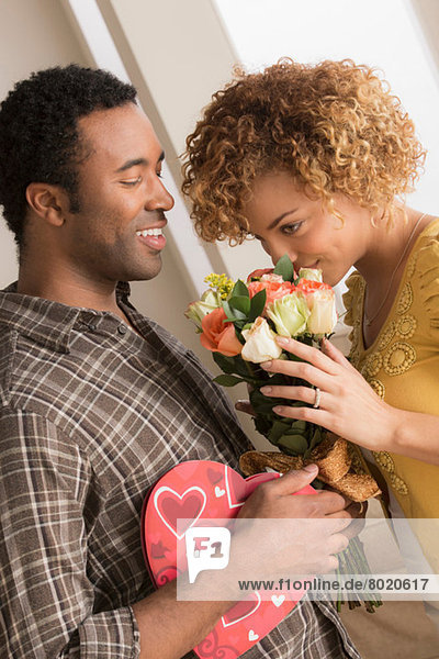 Mann schenkt Frau Blumen und Schokolade am Valentinstag