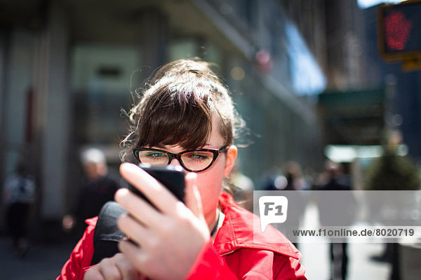 Frau auf der Stadtstraße schaut auf Smartphone