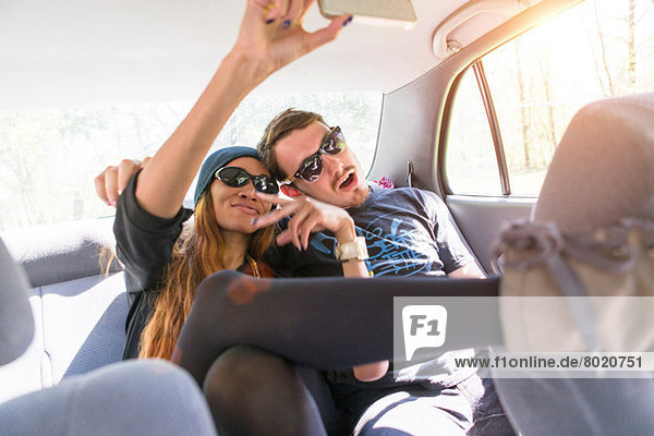 Paar auf dem Rücksitz im Auto fotografiert sich selbst