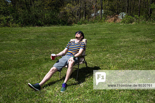 Mann auf Stuhl sitzend beim Sonnenbaden