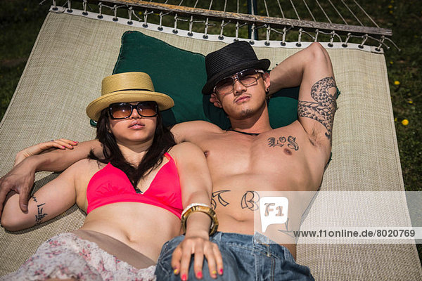 Paar mit Hüte und Sonnenbrille in der Hängematte liegend