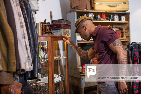 Junger Mann schaut in den Schrank im Vintage-Shop