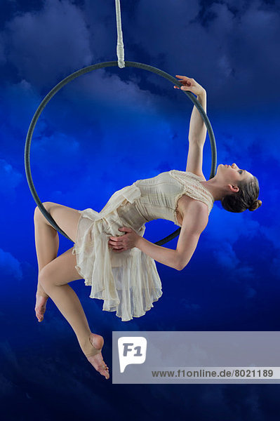 Aerialist auf Reifen vor blauem Hintergrund