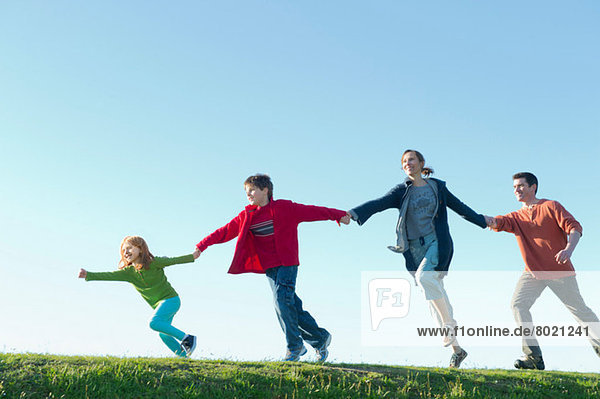 Eltern und zwei Kinder beim Laufen und Händchenhalten