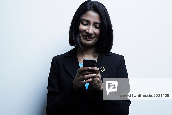 Studio-Porträt einer Geschäftsfrau beim Blick aufs Handy