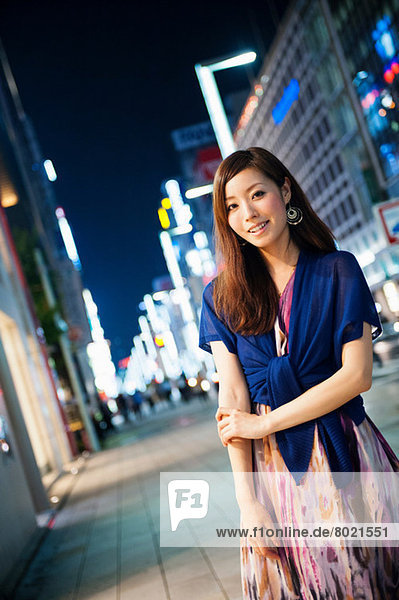 Portrait of young woman on city street at night