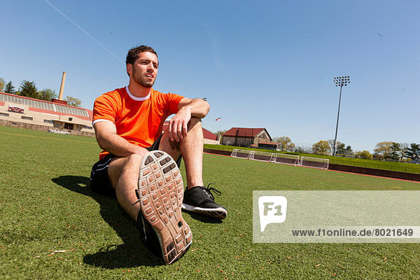 Junger Mann macht Pause auf Sportstadionrasen