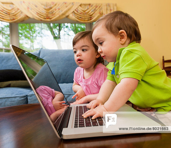Zwei junge Kleinkinder beim Spielen mit dem Laptop