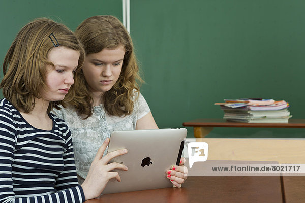 Zwei Schülerinnen im Klassenzimmer benutzen einen Tablet-PC