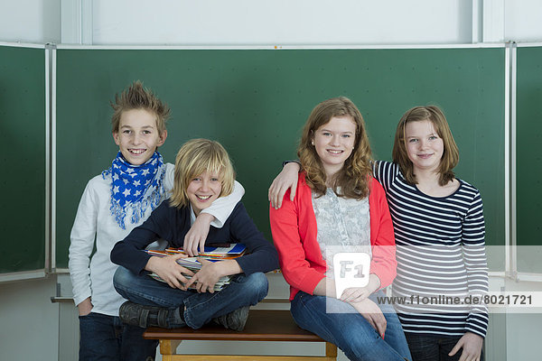 Vier lächelnde Schülerinnen und Schüler im Klassenzimmer