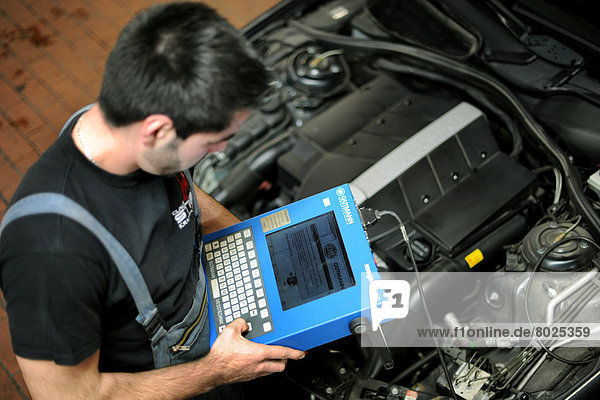 A car mechanic is analysing the engine of a car.