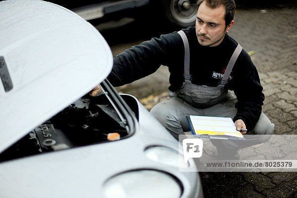 A car mechanic is examining the damage of a car  that has been involved in an accident.