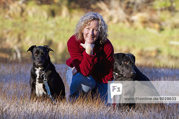 Portrait of a woman with her two black dogs in a field of frosty wild grass Coulterville california united states of america