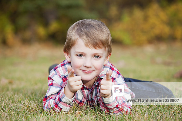 Portrait of a young boy laying on the grass in autumn Edmonton alberta canada