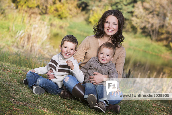 A mother with her two young sons in a park in autumn St. albert alberta canada
