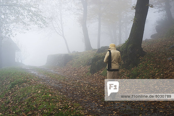 A woman walking down a foggy path in autumn Bellinzona ticino switzerland
