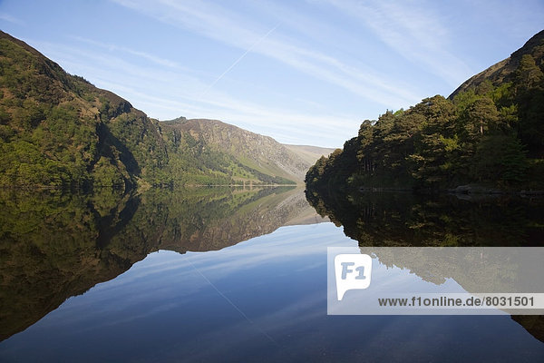 Shoreline of tranquil upper lake reflected in the water Glendalough county wicklow ireland