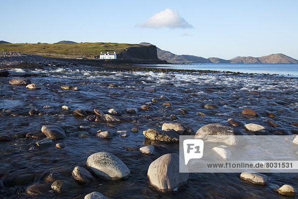 Rocks in the shallow water along the coast with a white house on the water's edge near waterville County kerry ireland