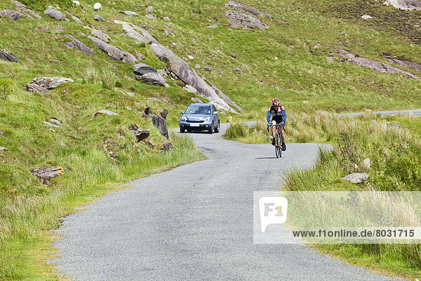 A cyclist and car on healy pass road County cork ireland