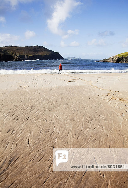 A woman standing on clogher beach in dingle County kerry ireland
