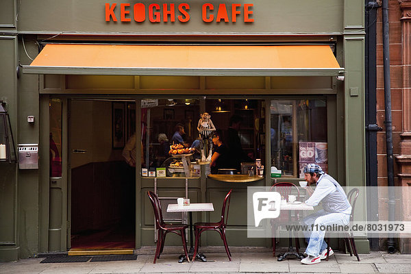 A man sits at an outdoor table of a cafe sipping coffee Dublin county dublin ireland