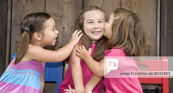 Three Young Chinese-Canadian Girls Sitting In A Row And Kissing  Ontario  Canada