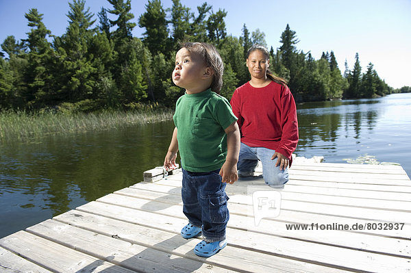 Native Aboriginal Mother On A Dock With Her Son In Shoal Lake  Ontario  Canada.