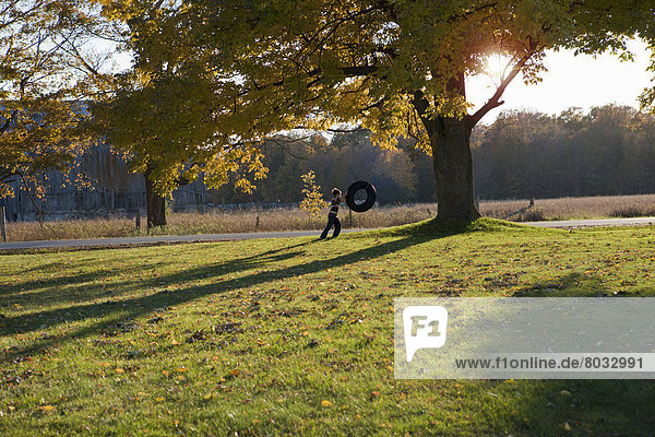 Boy Pushing A Tire Swing In The Fall