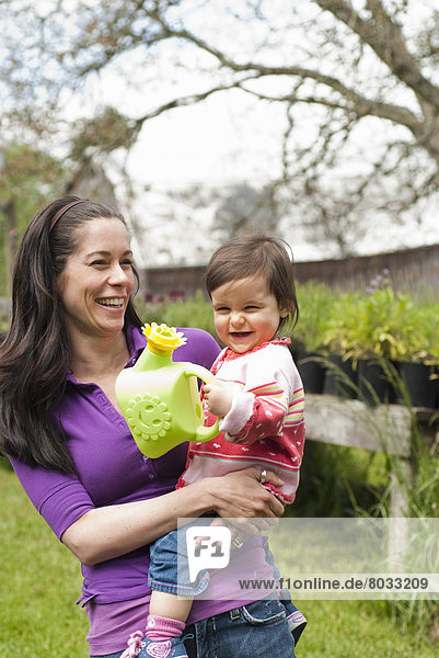 Mother And Daughter With Watering Can In Outside Garden  Vancouver British Columbia
