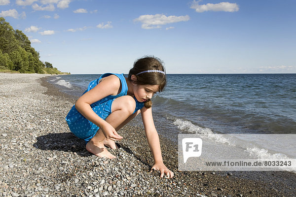 Young Girl Collecting Stones On The Beach By Lake Ontario  Ontario Canada