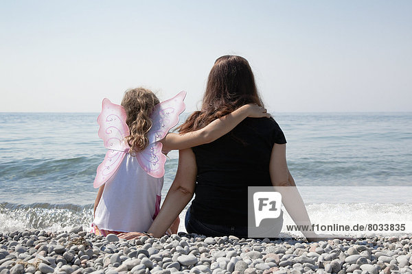 Grandmother and granddaughter sitting on a pebble beach on the shore of lake ontario Whitby ontario canada