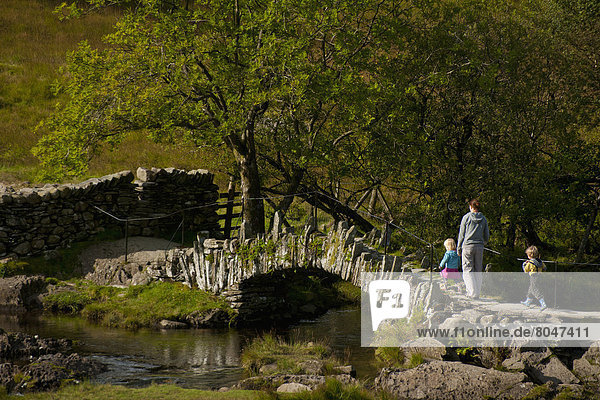 Mother and children crossing Slaters Bridge near Little Langdale  Lake District National Park  Cumbria  England  UK
