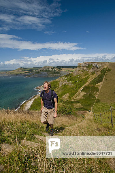 Walker going up stairs up to St Aldhelm's Head on South West Coastal Path  Purbeck  Dorset  UK