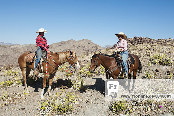 Two men horseback riding among desert landscape  Texas  USA