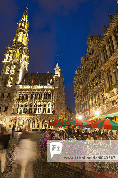 People eating and drinking at cafe tables at dusk in Grand Place  Brussels  Belgium