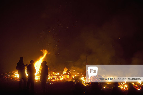 People in front of remains of large bonfire at Newick Bonfire Night  Newick  East Sussex  England  UK