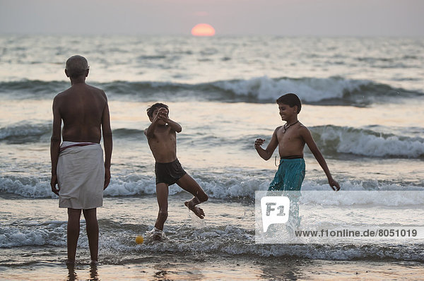 India  Karnataka  boys playing  Gokarna  Hindu pilgrim praying by ocean at sunset